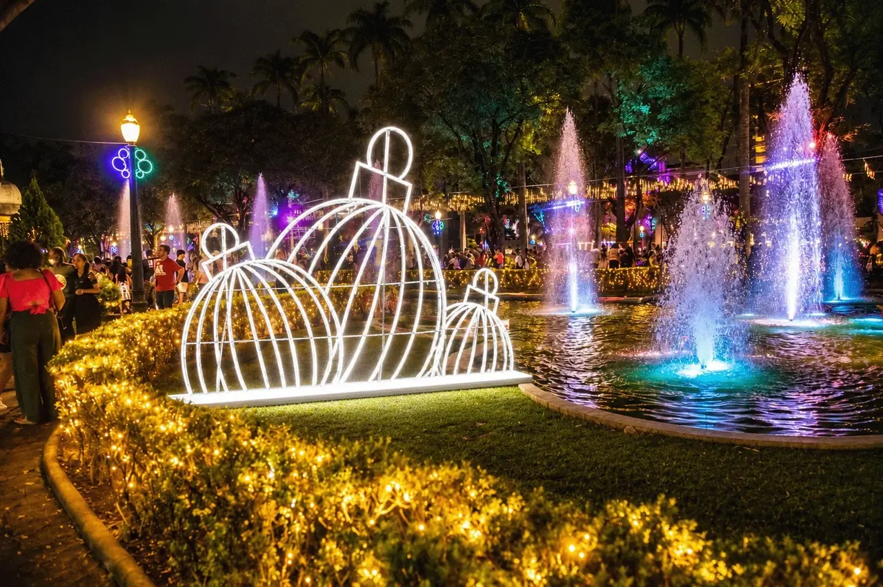 Bolas luminosas junto à fonte, com cerca viva acesa