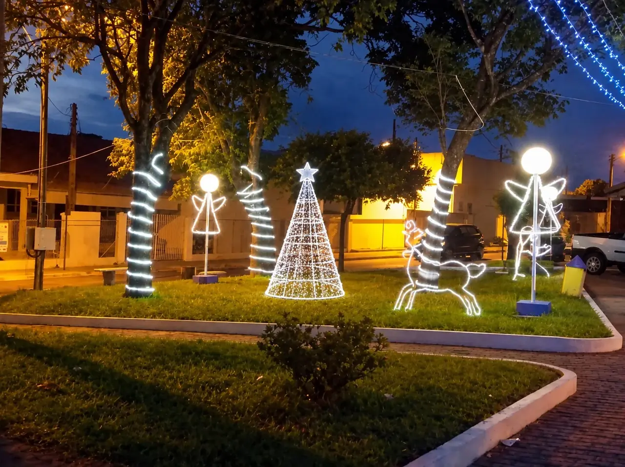 Praça de bairro com anjos, rena e árvore cone